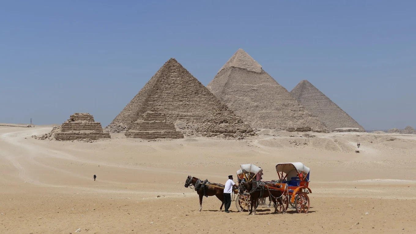 Giza Piramitleri önünde develerle çekilmiş çöl manzarası.